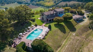 An aerial view of a property with a swimming pool, lounge area, and a large house surrounded by greenery. - Tenuta Montiepoli 12 3 Emma Villas (Valfabbrica)