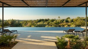 A covered outdoor area with a pool, lounge chairs, and a view of a natural landscape. - Villa Amore 8 Emma Villas (Avola)