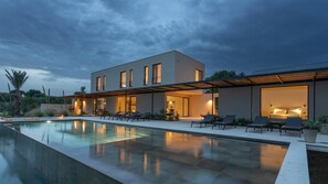Une maison moderne à deux étages dotée d’une piscine, d’un espace salon extérieur et d’un patio couvert.