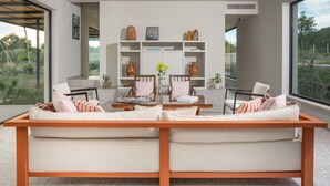 A modern living room with a sofa set, a coffee table, and a bookshelf. - Villa Amore 8 Emma Villas (Avola)