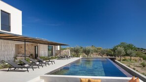 A modern poolside area with lounge chairs and a clear blue pool.