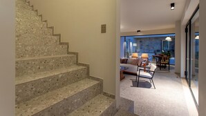 A staircase with a terrazzo finish leading to a modern living area with a sofa, chairs, and a dining table. - Villa Amore 8 Emma Villas (Avola)