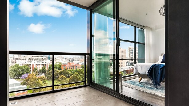 A modern apartment with a large balcony, a bed, and a view of the cityscape. - Darlinghurst — Newly renovated 1BR + Parking (City of Sydney)