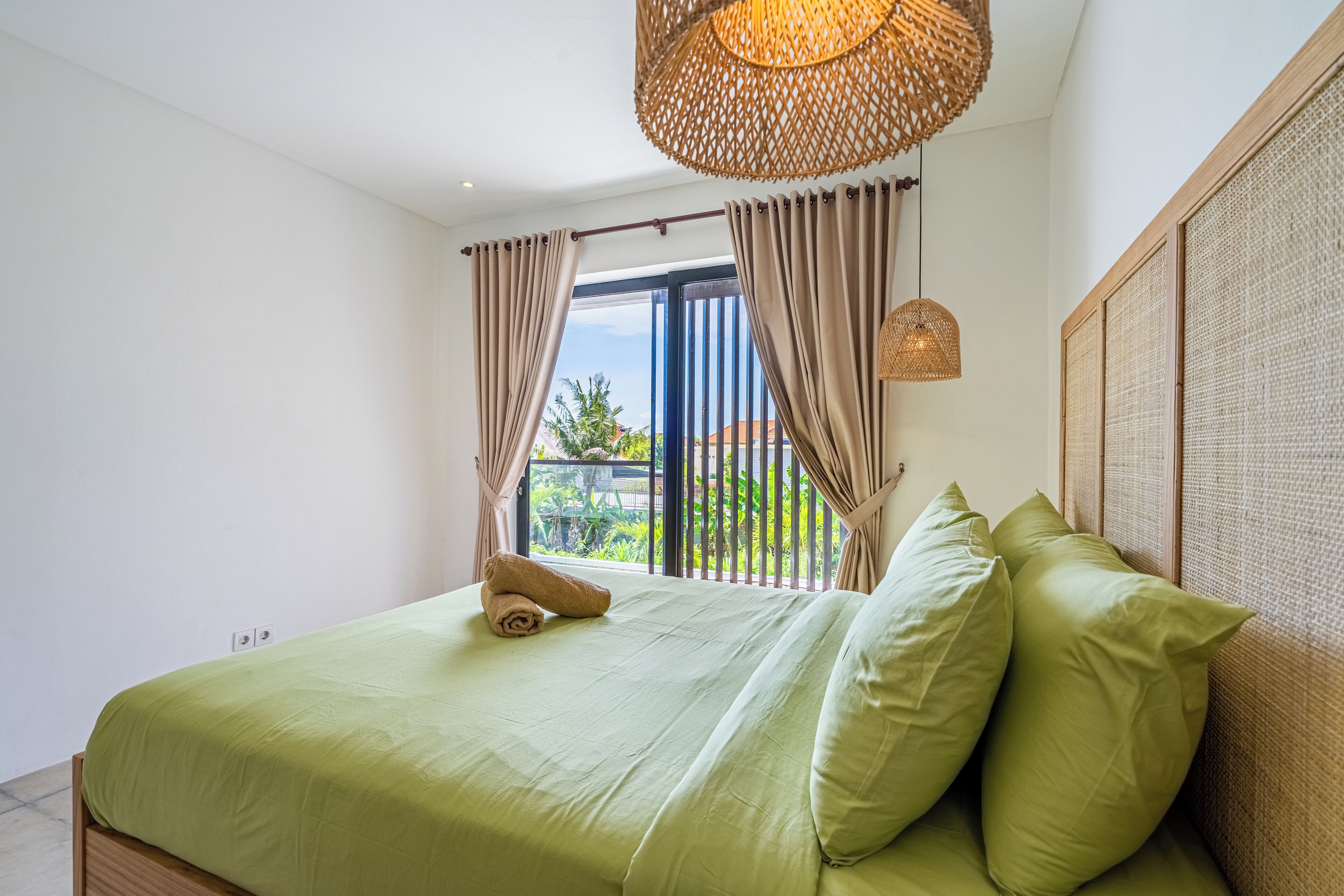 Un dormitorio con cama, cortinas, lámpara colgante y vistas al exterior.