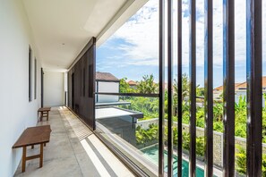Un balcón con vistas a una piscina y vegetación.