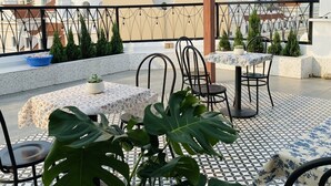 A rooftop terrace with outdoor seating, potted plants, and a view of the cityscape. - Palette Collect's Boutique Hotel Ha Long (Bai Chay)