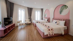 A modern bedroom with two beds, a TV, and a seating area. - Palette Collect's Boutique Hotel Ha Long (Bai Chay)