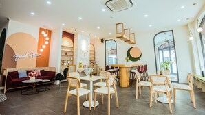 A modern cafe interior with a red sofa, round tables, wicker chairs, and a neon sign. - Palette Collect's Boutique Hotel Ha Long (Bai Chay)