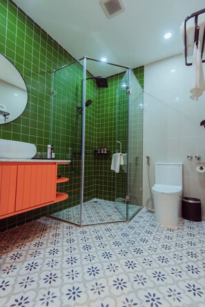 A bathroom with a shower enclosure, a sink with a mirror, and a toilet.