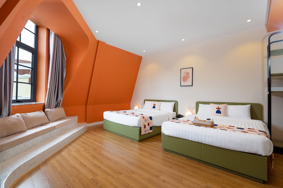 Ein modernes Hotelzimmer mit zwei Betten, einer Sitzecke und einem großen Fenster.