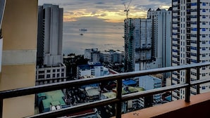 A cityscape with high-rise buildings, a construction crane, and a sunset over the water. - Manila Bay City View Room with Free Pool (Manila)