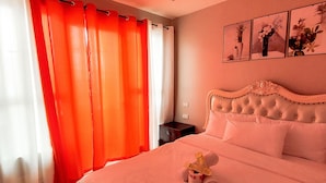 A hotel room with a large bed, orange curtains, a nightstand, and a wall with three framed pictures. - Manila Bay City View Room with Free Pool (Manila)