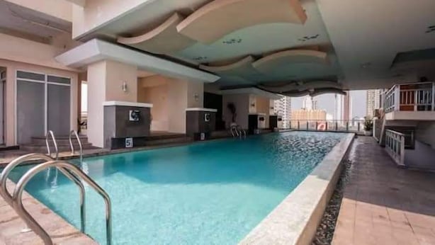 A swimming pool with a clear blue water, surrounded by a tiled deck and a covered area with a curved ceiling. - Manila Bay City View Room with Free Pool (Manila)