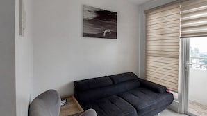 A modern living room with a dark sofa, a grey armchair, and a ceiling fan. - Manila Bay City View Room with Free Pool (Manila)