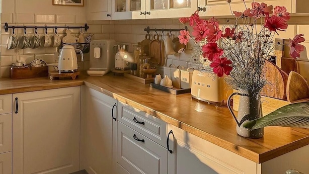 A kitchen with white cabinets, a wooden countertop, and a vase with flowers. - Winnipeg Holiday (Winnipeg)