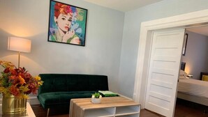 A room with a green sofa, a white coffee table with shelves, a painting on the wall, and a door leading to another room. - Winnipeg Holiday (Winnipeg)