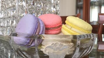 A glass bowl containing three macarons on a reflective surface.