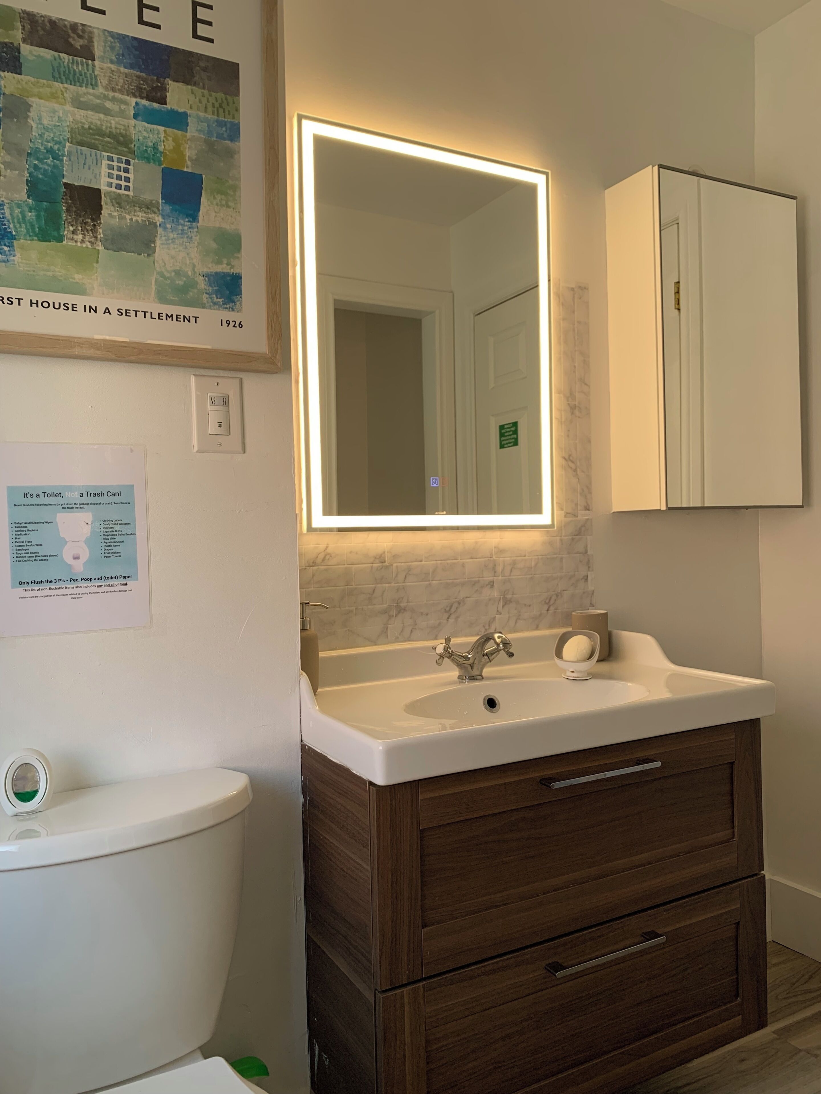 A bathroom with a toilet, a sink with a mirror, and a cabinet.
