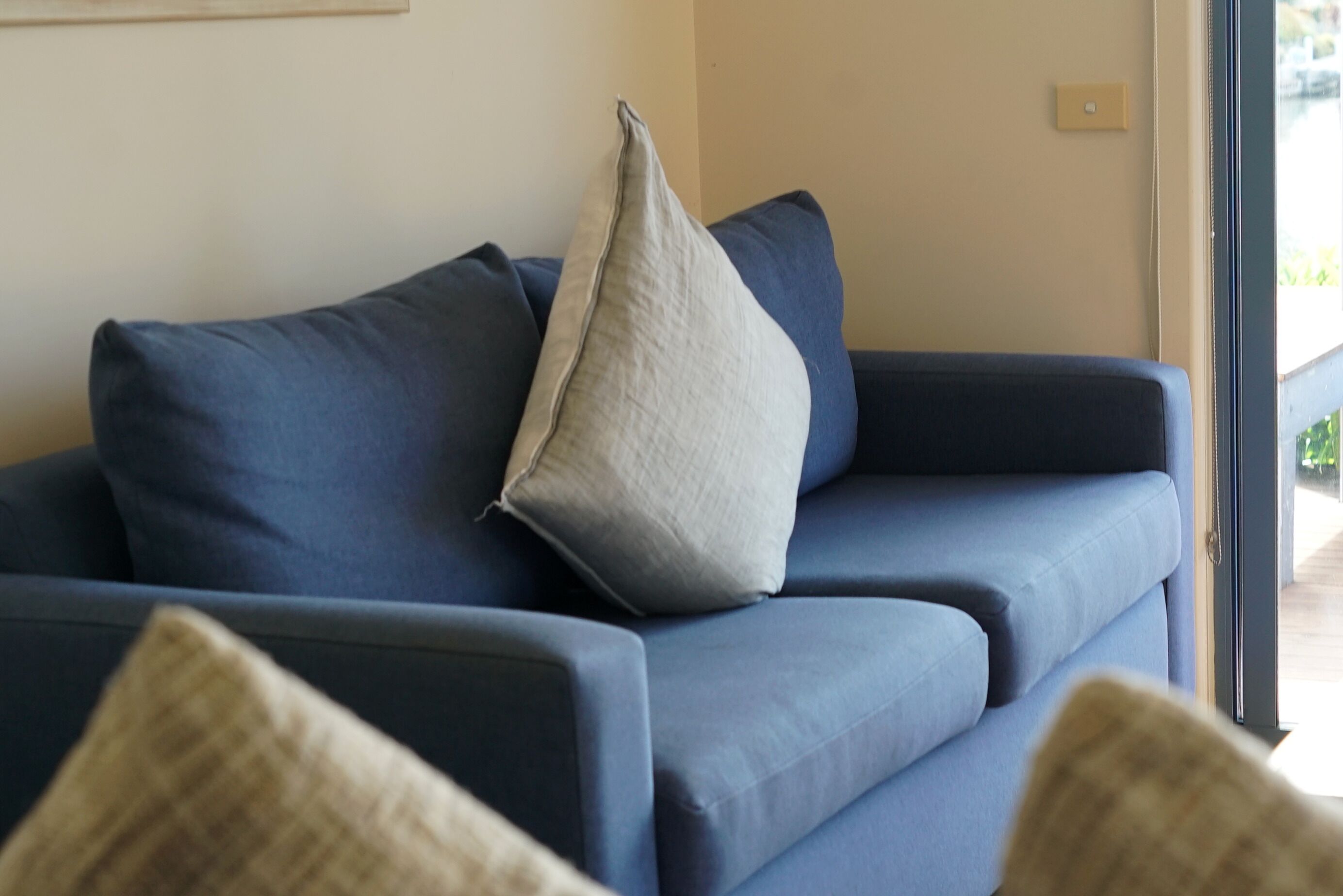A blue sofa with a light grey pillow and a dark grey pillow.