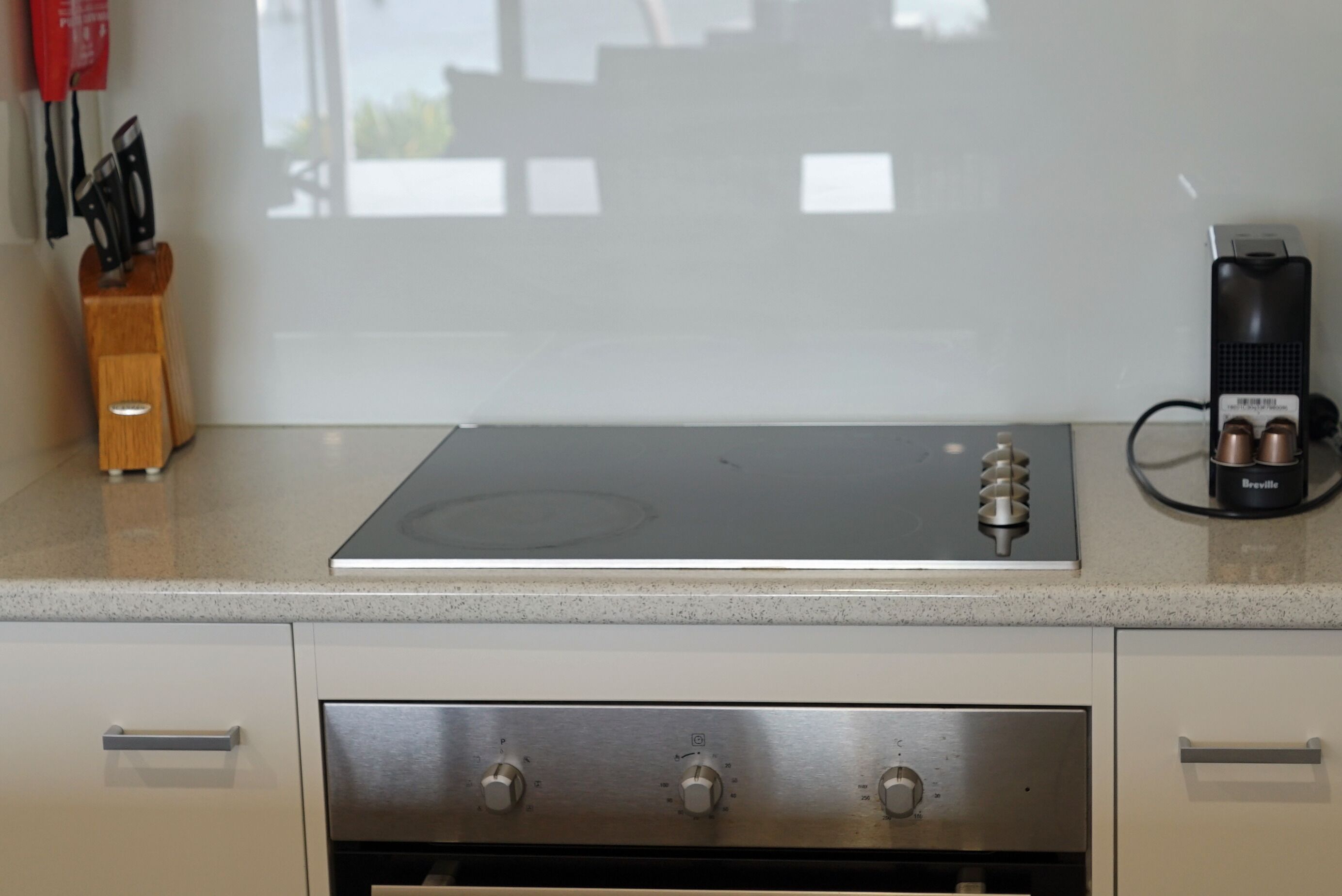 A kitchen with a built-in stovetop, a Breville coffee maker, and a knife block on the countertop.
