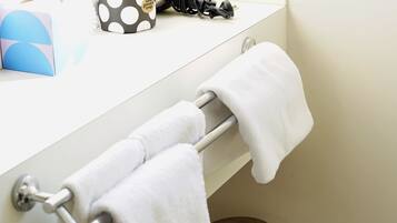 A bathroom with a white towel rack holding two towels, a trash bin, and a blue box with a geometric design.