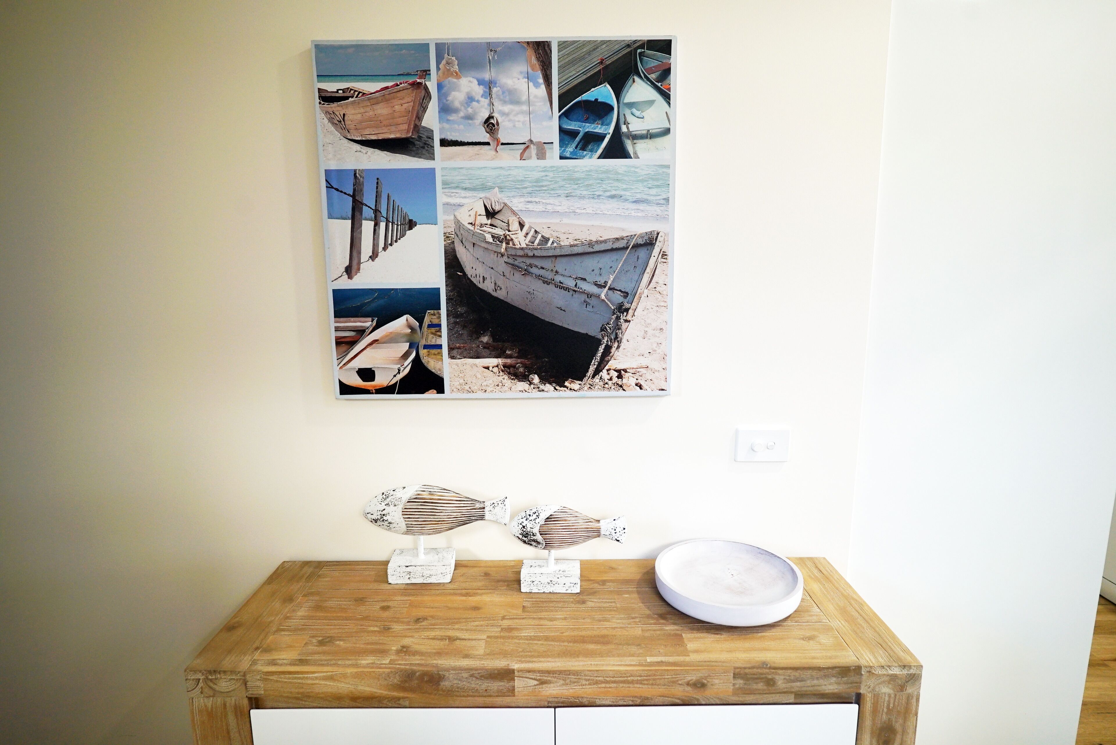 A wooden table with a white plate and two fish-shaped sculptures.