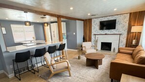 A modern living room with a sofa, chairs, a coffee table, a fireplace, and a TV mounted on the wall. - Guest Favorite- Denver Getaway Gem with Grill, Corn Hole, Basketball Court (Denver)