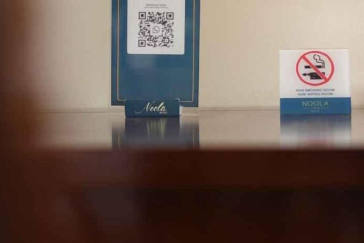 A QR code, a no-smoking sign, and a sign with the brand name 'Noola.'