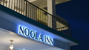 The exterior of Noola Inn with a balcony and a sign.