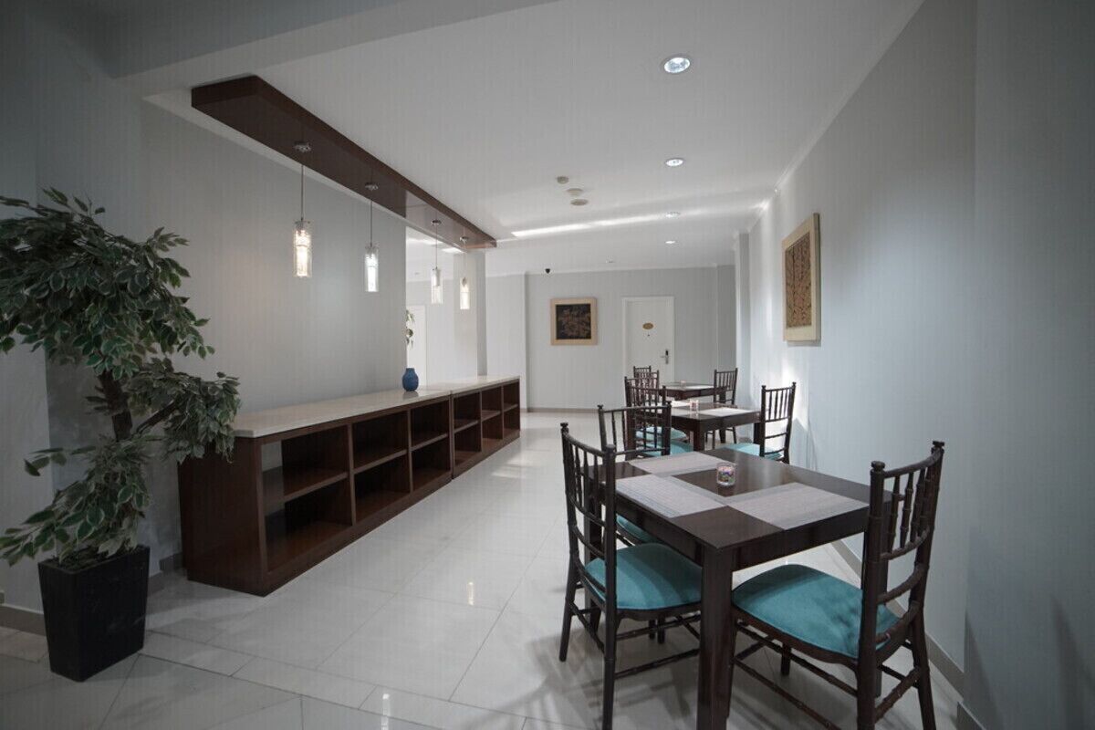 A dining area with a wooden table and chairs, a potted plant, and a built-in shelving unit.