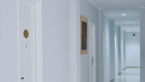 A clean, modern hallway with white walls and a tiled floor, leading to multiple doors.