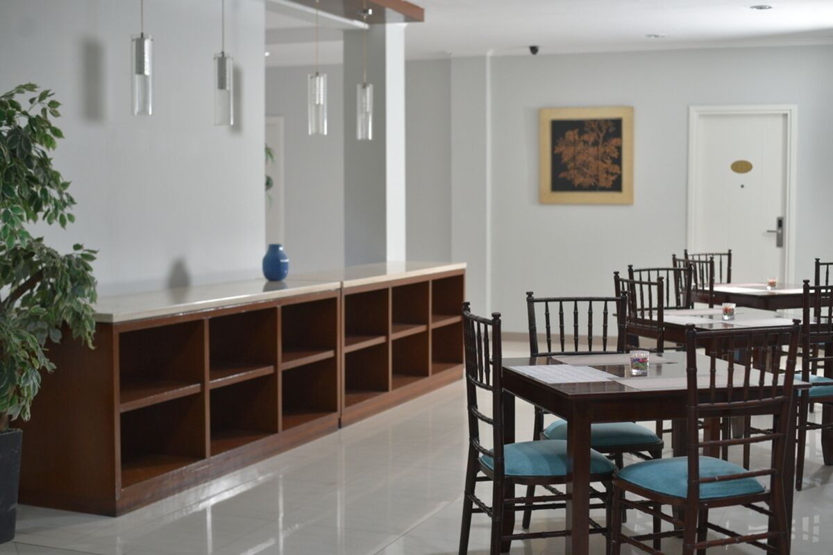 Un comedor con un aparador de madera, sillas azules y lámparas colgantes.