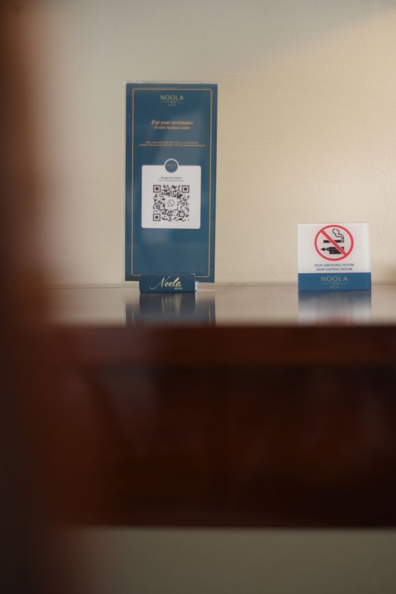 A QR code on a blue card with the text "NOOLA" and a no-smoking sign next to it.