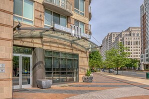 1200 WEST offers a sleek, modern entrance with a glass door and double doors, set amidst a beautifully maintained outdoor space with potted plants.