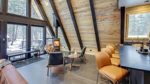Un interior acogedor con techo de madera, ventanas amplias, chimenea y zonas de estar.