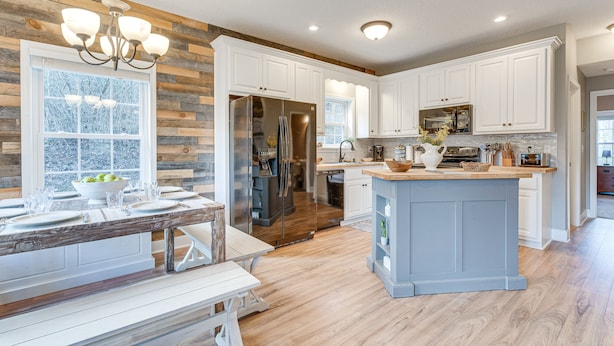 A modern kitchen with white cabinetry, a central island, and a wooden accent wall. - Hammocks & Forest Views: Creekside Murphy Retreat (Murphy)