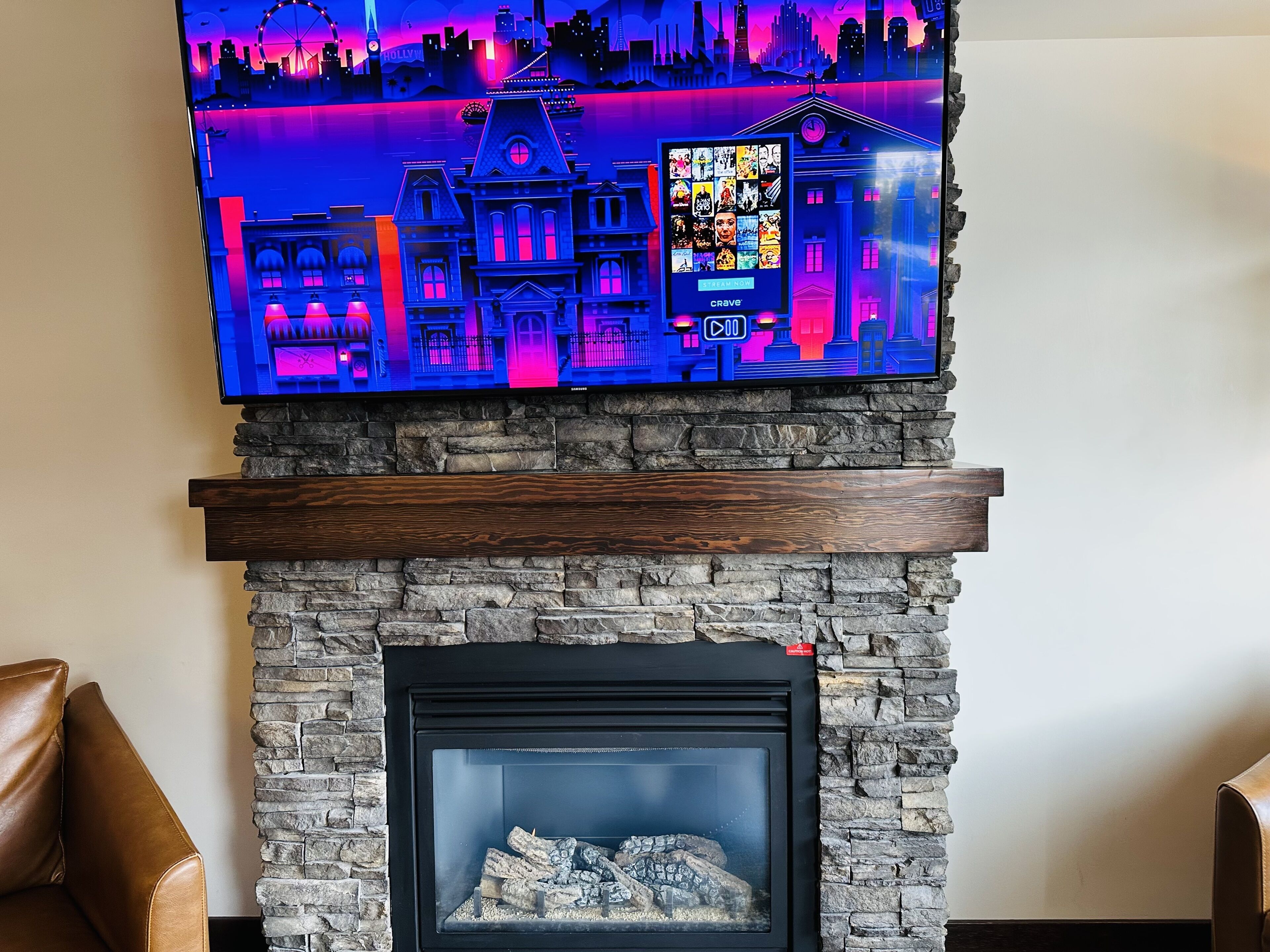 Una chimenea con revestimiento de piedra y un televisor de pantalla plana montado encima, mostrando un paisaje urbano.