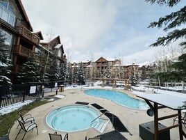 Um resort com duas piscinas, edifícios de madeira e árvores cobertas de neve.