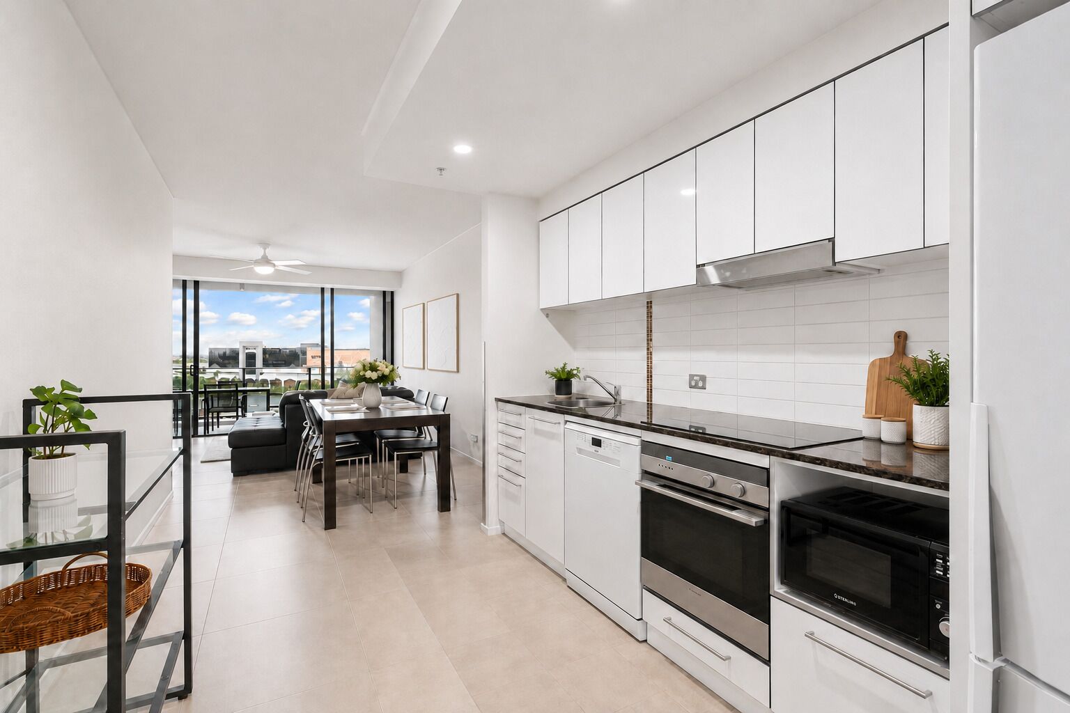A modern kitchen with white cabinetry, stainless steel appliances, and a dining area with a glass table.