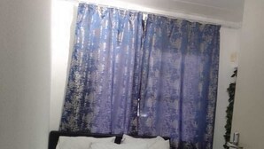 Une chambre à coucher avec un lit, des oreillers blancs et un rideau bleu.