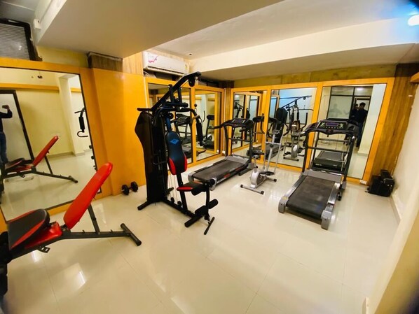 A gym with various exercise equipment, including treadmills, weight machines, and benches. - Mak Hotel (Bengaluru)