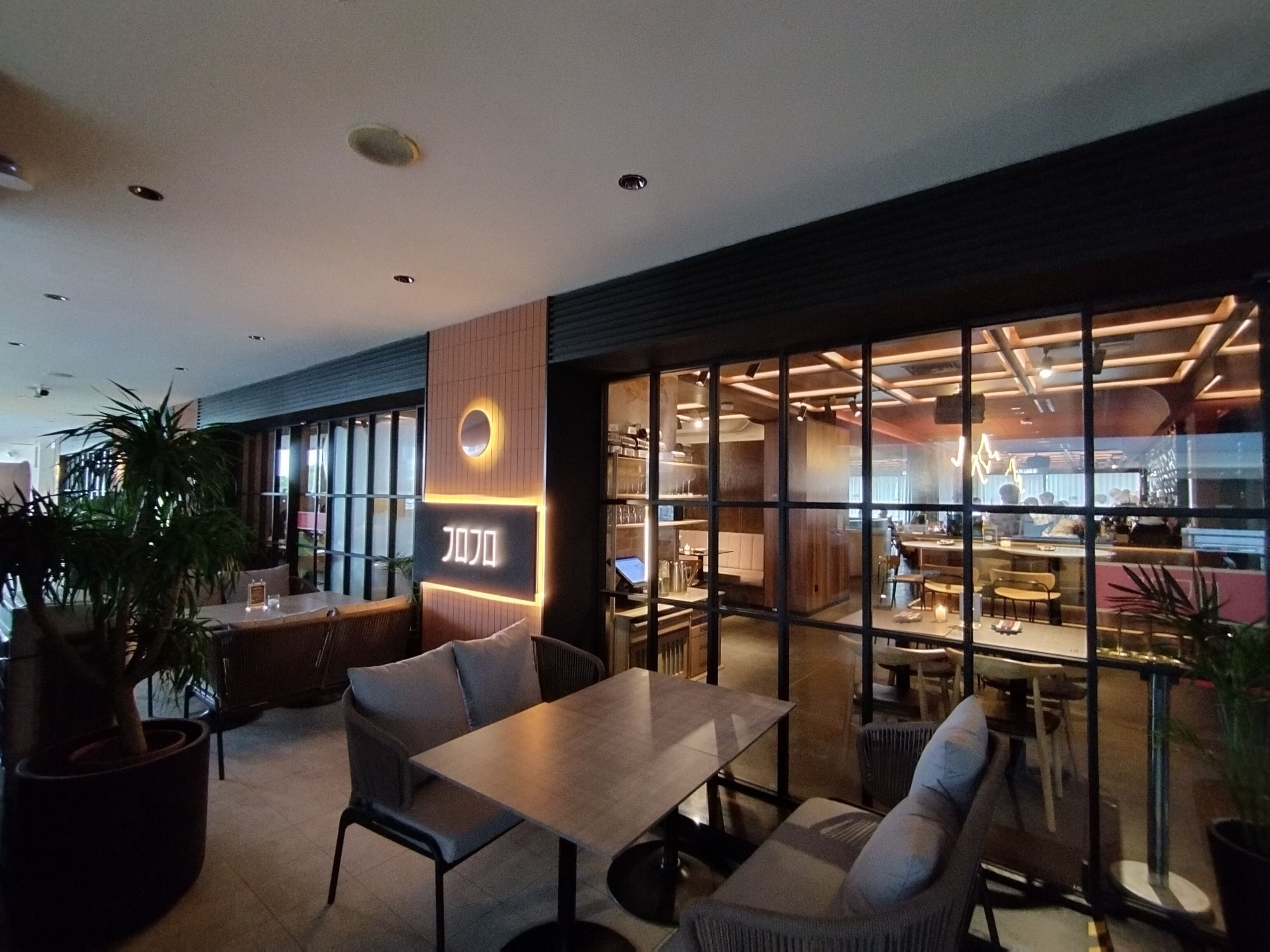 A modern restaurant interior with a bar area, seating arrangements, and a visible menu board.