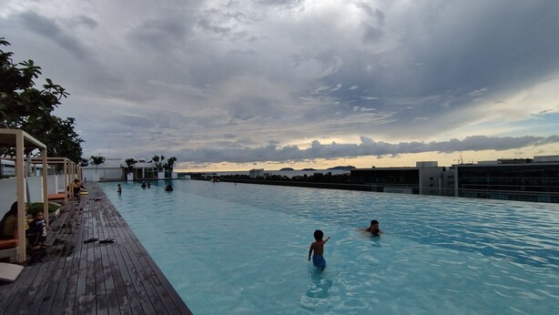 A swimming pool with a wooden deck and a view of the city skyline. - reStary Blue Game Themed Homestay (Kota Kinabalu)