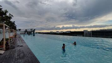 A swimming pool with a wooden deck and a view of the city skyline.