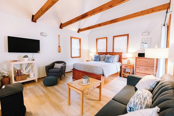 A cozy bedroom with a bed, bedside table, lamp, and a TV mounted on the wall.