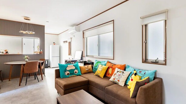 Una sala de estar moderna con un sofá modular, un comedor y una cocina al fondo.