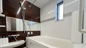 Un baño moderno con una bañera grande, un tocador con espejo y un ventanal que proporciona luz natural.
