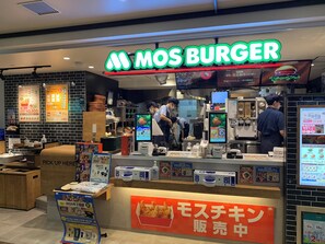 Un restaurante de comida rápida con un letrero luminoso que dice "MOS BURGER".