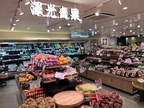 Interior de una tienda de comestibles con diferentes secciones de frutas y verduras y etiquetas de precio visibles.