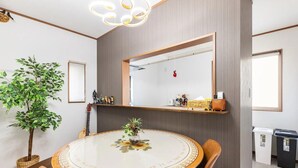Un comedor con una mesa redonda, sillas, una planta en maceta, un espejo y una repisa con adornos.